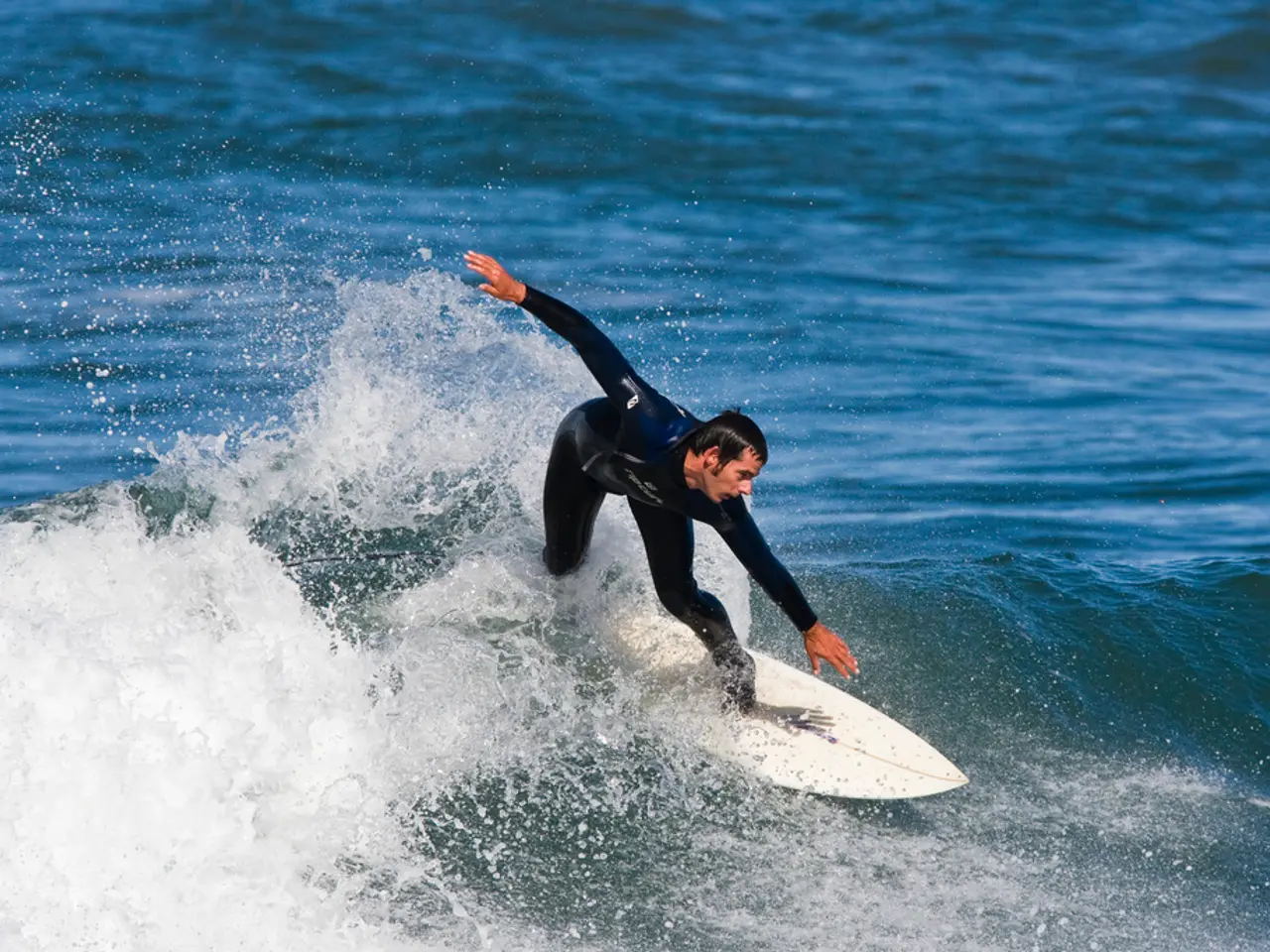 In this image, we can see a person is surfing with surfboard on the water.