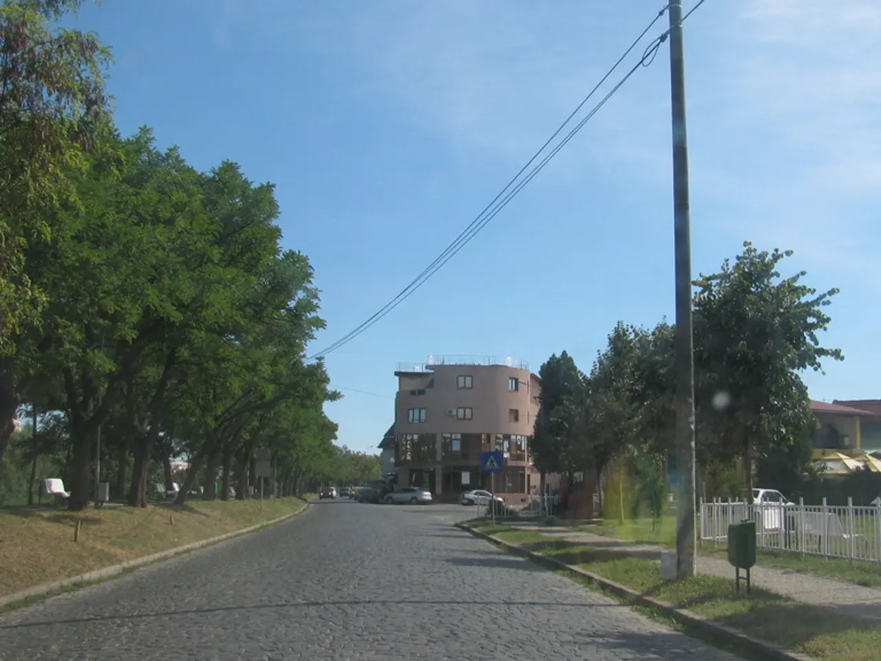 In the image we can see there are many vehicles. This is a road, grass, fence, electric pole,...
