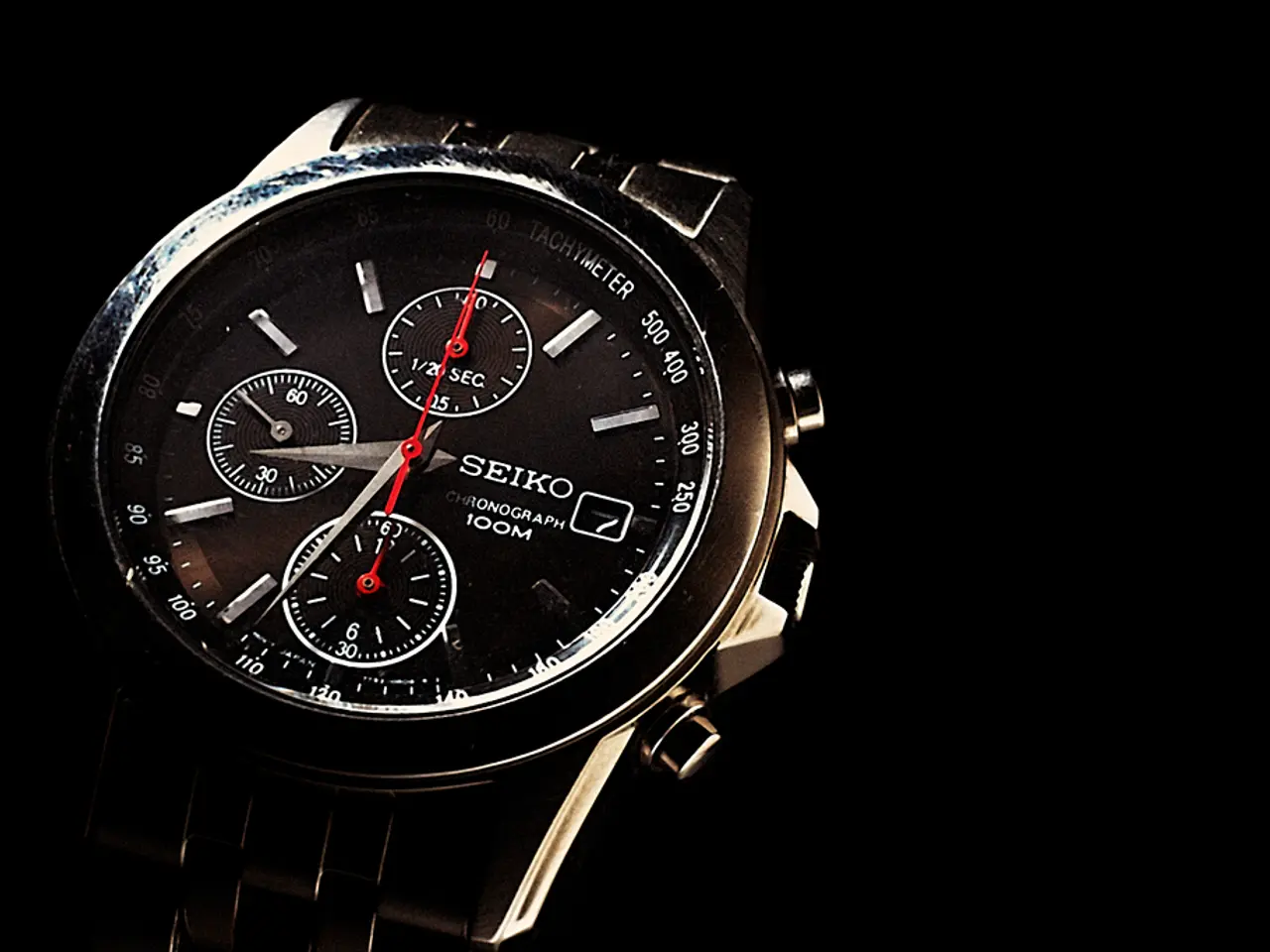 In this image I can see a wrist watch which is black, white and red in color. I can see the black...