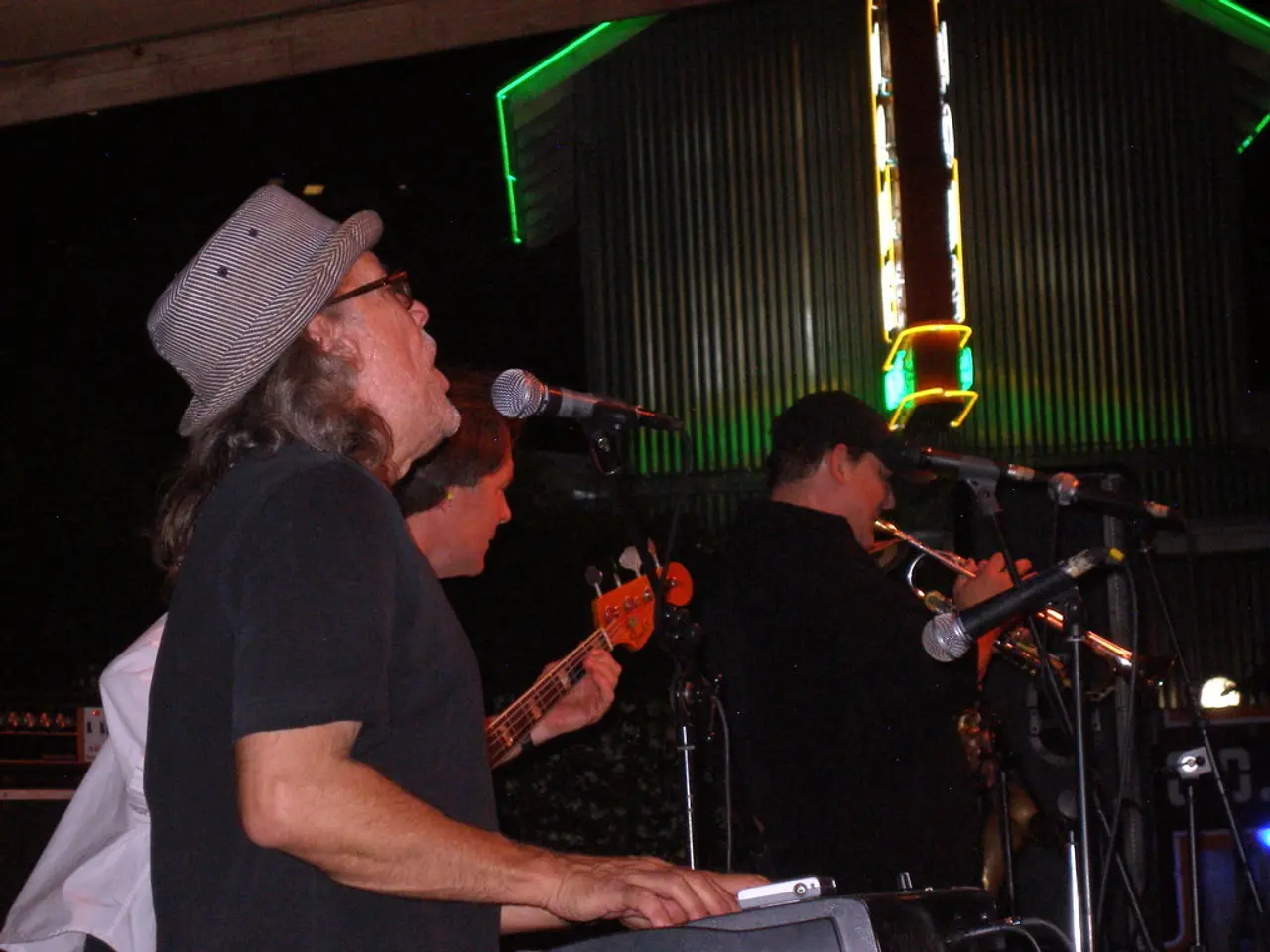In this image we can see few people playing musical instruments and there are few mics in front of...