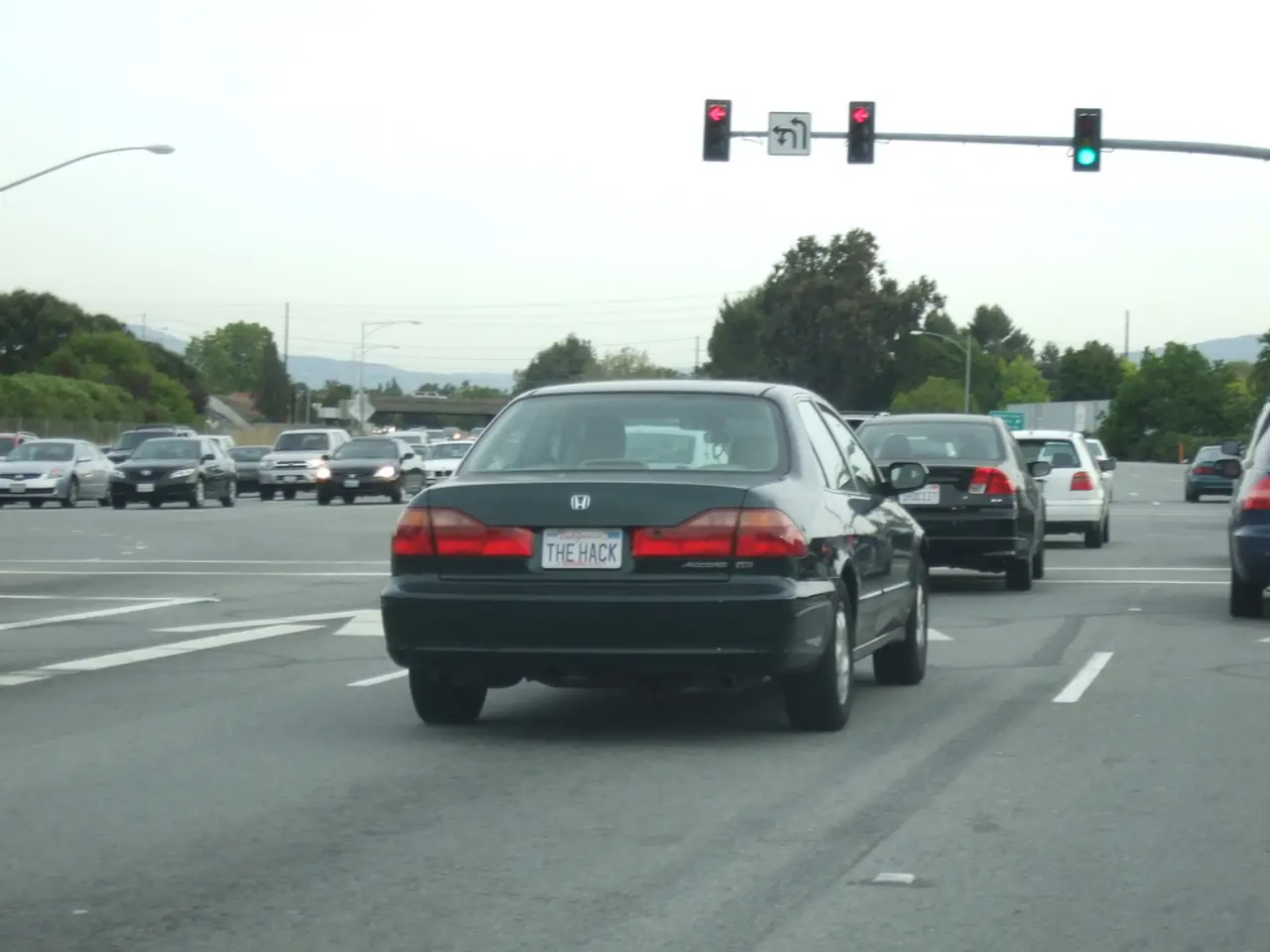 In this image we can see a road. On which there are many vehicles. In the background of the image...
