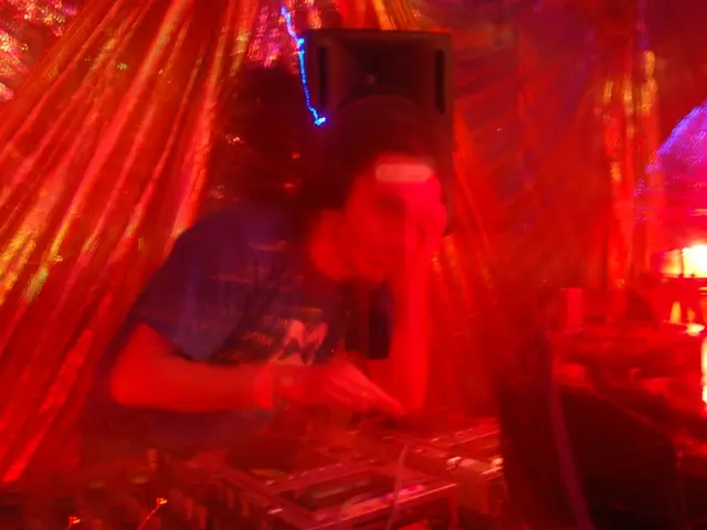 In this image we can see a man playing a dj and there are lights. We can see a speaker.
