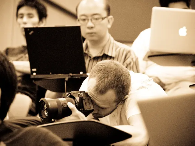 In this image I see a person who is holding a camera and in the background I see few people and...