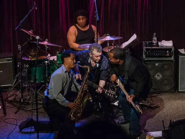 There are so many people on stage playing musical instruments behind them there is a sound box and...