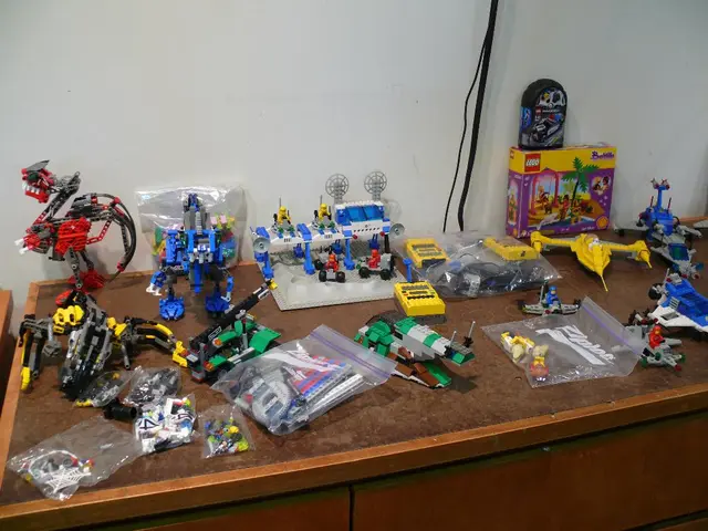 In this image there is a table having few toys on it. Behind it there is wall hiding wires. On the...