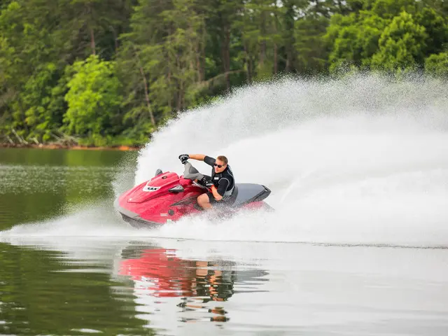 In the center of the image we can see a man riding on the jet ski. At the bottom there is water. In...